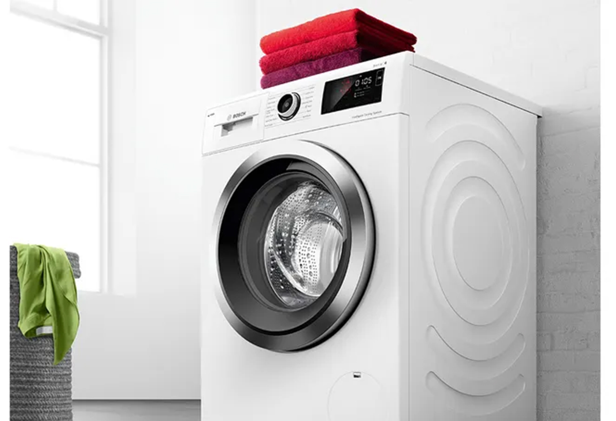 Απεικονίζεται το πλυντήριο ρούχων Bosch  WGG042L9GR πάνω στο οποίο είναι τοποθετημένες 3 πετσέτες, στην απόχρωση του κόκκινου.